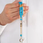 ⁦سبحة من حجر الفيروز مطلية بالذهب ومزينة بشرابة من الزركون⁩ - الصورة ⁦3⁩